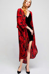 Model wearing long black crepe kimono with red leaf prints tilting her head